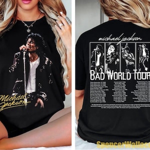 May include: A black t-shirt featuring a graphic of Michael Jackson on the front with his name in gold script. The back displays four black and white photos of the artist, the text "Michael Jackson BAD WORLD TOUR," and a list of tour dates.