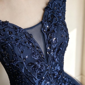 Three quarter side angle layout of a glamorous embroidered navy tulle princess dress with sparkling glitter coatings.