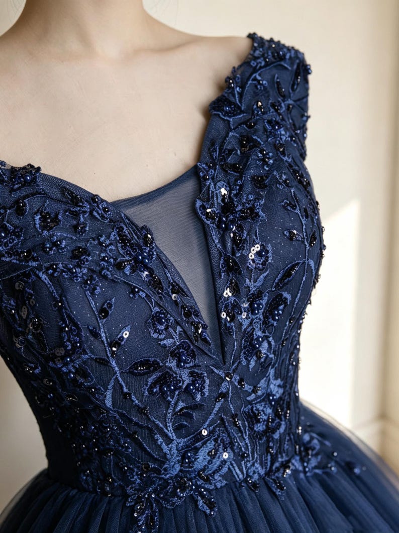 Three quarter side angle layout of a glamorous embroidered navy tulle princess dress with sparkling glitter coatings.