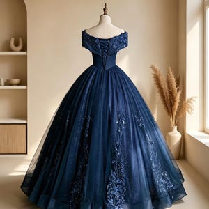Detailed close up of the illusion plunging V-neckline mesh and off-the-shoulder embroidered sleeves on a navy gown.