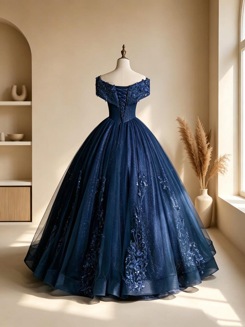 Detailed close up of the illusion plunging V-neckline mesh and off-the-shoulder embroidered sleeves on a navy gown.