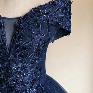 Magnificent front overview of a one size glittering navy blue starry night ballgown displayed in a serene studio showroom.