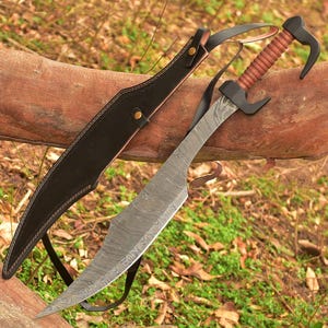 May include: A Damascus steel blade sword with a curved, pointed tip and a distinct wavy pattern. The handle is wrapped in brown cord with a black pommel and guard. A black leather sheath with gold-colored metal rivets accompanies the sword.