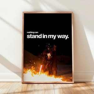 Könnte beinhalten: Ein rechteckiger Wandkunstdruck in einem Holzrahmen, der eine dunkle Figur in schwarzer Rüstung zeigt, die ein leuchtendes rotes Lichtschwert inmitten von Flammen hält. Der Text "nothing can stand in my way." steht in weißen Buchstaben oben.