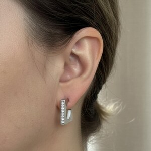 May include: A set of three ceramic mugs with a speckled, matte finish. The mugs are in shades of cream, light gray, and dark gray. Each mug has a simple, modern design and a rounded handle. The mugs are stacked on top of each other.