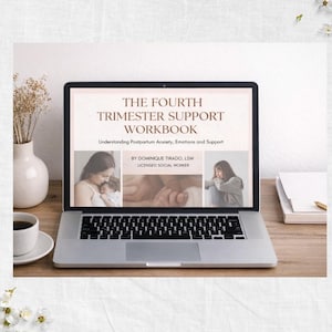 May include: A laptop displays a workbook titled "THE FOURTH TRIMESTER SUPPORT WORKBOOK." The screen shows images and text about postpartum anxiety, emotions, and support. A coffee cup, vase with dried flowers, and a stack of books are on the wooden desk.