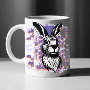 Könnte beinhalten: Weiße Keramiktasse mit einer Schwarz-Weiß-Illustration eines Hasen. Der Hase hat lange Ohren und detailliertes Fell. Der Hintergrund zeigt ein geometrisches Design in Lila, Orange und Grau.