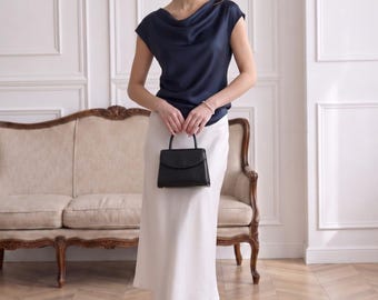 Blusa feminina com decote drapeado, em seda, com mangas curtas elegantes, ideal para o ambiente de trabalho casual e executivo. Um toque de luxo discreto.