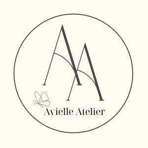 May include: A circular logo with a cream background features the text "Avielle Atelier" in a serif font. Two stylized "A" letters are in the center, with a butterfly illustration to the left. The logo is enclosed by a dark gray circle.
