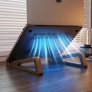 May include: A silver laptop resting on a dark wood grain laptop stand. The underside of the laptop features ventilation slots with a bright blue light effect emanating from them, suggesting active cooling airflow directed downward toward the stand.