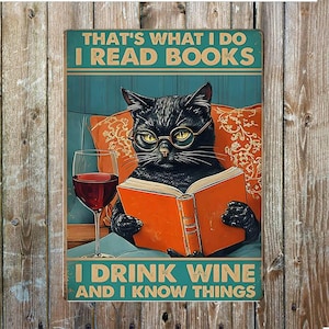 May include: A metal sign featuring a black cat wearing spectacles, reading a book, and holding a glass of wine. The sign reads "THAT'S WHAT I DO I READ BOOKS I DRINK WINE AND I KNOW THINGS" in teal and white. The background is a wooden wall.