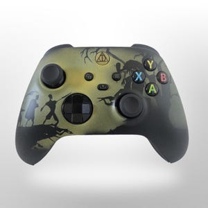 May include: A custom Xbox controller with a green and black design. The controller features silhouettes of characters and symbols from a popular fantasy series. The buttons are colored green, blue, yellow, and red.
