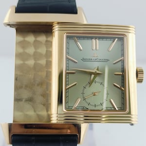 Peut inclure: Montre-bracelet rectangulaire dorée avec un cadran vert clair et un bracelet en cuir noir. Le cadran de la montre présente des aiguilles et des index dorés, avec un petit cadran des secondes. Une montre de luxe.