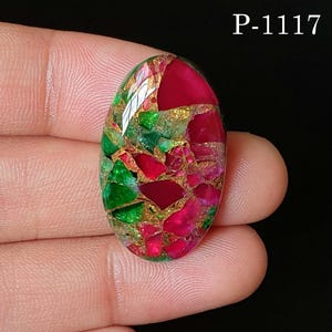 May include: An oval-shaped cabochon gemstone featuring a mosaic pattern of vibrant magenta and emerald green segments separated by metallic gold-colored veins. The stone is labeled with the text P-1117 in the upper right corner of the image.