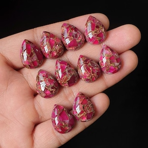 May include: A collection of nine teardrop-shaped cabochons featuring a vibrant mosaic pattern of deep magenta and bright pink segments interspersed with metallic copper-colored veins, each polished to a smooth, reflective, and faceted finish.