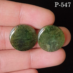 May include: Two round, polished green gemstones with a marbled appearance. The stones have a glossy finish and are held between fingers against a dark background. The text "P-547" is in the upper right corner.