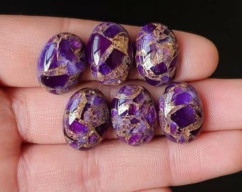 Pode incluir: Sete pedras preciosas ovais com um padrão de mosaico de roxo profundo e dourado. As pedras são polidas e lisas, com um acabamento brilhante. As pedras preciosas são seguradas em uma mão contra um fundo escuro.
