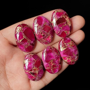 May include: Six oval-shaped cabochons featuring a vibrant magenta and deep pink base color with an intricate network of metallic gold veining throughout each stone. The polished surfaces have a high-gloss finish that reflects light across the faceted-like patterns.