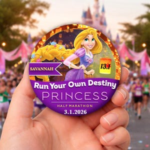 Op de afbeelding: Een ronde, paarse Princess halve marathon medaille met Rapunzel. De medaille leest "Run Your Own Destiny" en "Savannah 3.1.2026". De achtergrond toont een kasteel en hardlopers.