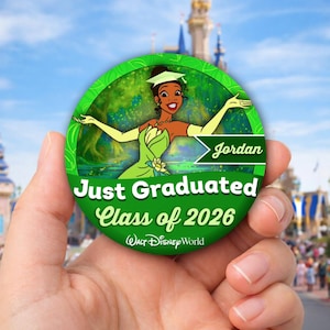 May include: A green and white round button featuring a cartoon image of Princess Tiana in a graduation cap. The button reads "Just Graduated Class of 2026" and "Jordan" with the Walt Disney World logo.