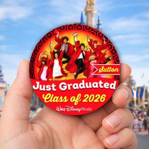 May include: A round, red button with the text "Just Graduated Class of 2026" and "Walt Disney World." The button features a group of people in red graduation robes. The name "Sutton" is also visible.