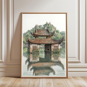 Op de afbeelding: Een ingelijste aquarelillustratie van een traditioneel Oost-Aziatisch paviljoen met een bruin pannendak met meerdere niveaus, gelegen boven kalm water. De structuur heeft gedetailleerde rasterramen en wordt omringd door groene heuvels en bomen.