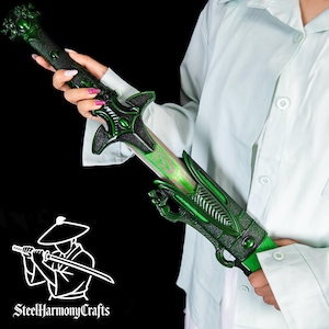 Könnte beinhalten: Ein grünes und schwarzes Fantasy-Schwert mit aufwendigen Drachenmotiven. Die Klinge hat einen leuchtend grünen Effekt. Griff und Parierstange weisen kunstvolle Designs auf. Das Logo "SteelHarmonyCrafts" ist sichtbar.
