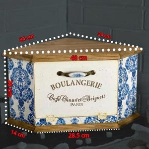 May include: A corner bread box with a wooden top and base, featuring blue and white floral patterns on the sides. The front panel is cream-coloured with the text BOULANGERIE, Cafe Chaud et Beignets, PARIS, and a handle. Dimensions are 34 cm, 48 cm, 26 cm, 14 cm, and 28.5 cm.
