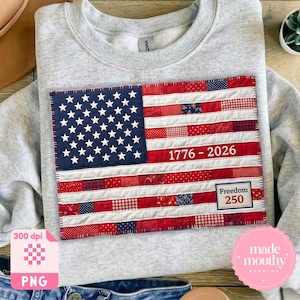 May include: A pale grey sweatshirt featuring a sewn-on American flag design. The flag is a patchwork of red, white, and blue fabrics, with the text "1776-2026" and "Freedom 250" on it.
