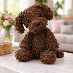 May include: A brown plush dog toy with a curly texture sits on a white surface. The stuffed animal has black eyes and a black nose. The dog is sitting upright with its head tilted slightly to the side.
