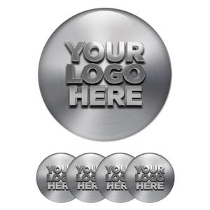 Może przedstawiać: Zestaw metalicznych, srebrnych, okrągłych guzików z tekstem "YOUR LOGO HERE" w efekcie 3D. Projekt powtórzony na mniejszych guzikach poniżej.