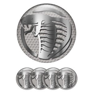 Peut inclure: Ensemble de cinq emblèmes argentés avec un motif de cobra. Le cobra est dans un cercle avec un fond en nid d'abeille. Ces emblèmes sont probablement destinés à l'automobile ou à la décoration.