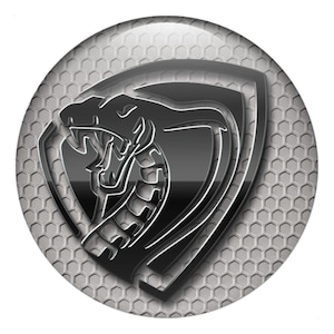Peut inclure: Un emblème circulaire représentant une tête de cobra stylisée dans un bouclier. Le design est en nuances de gris et de noir, avec un aspect métallique. Le fond présente un motif en nid d'abeilles.