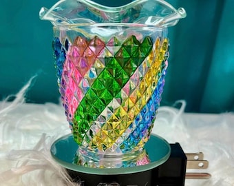 Könnte beinhalten: Ein Wachswärmer aus Glas mit einer rautenförmigen, mehrfarbigen Oberfläche in Rosa, Grün, Gelb und Blau. Die Oberseite hat einen gewellten Rand und die Basis ist schwarz mit einem Stecker. Der Text W-828 ist oben links zu sehen.