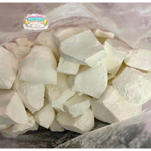 May include: Close-up of a clear bag filled with large, irregularly shaped white chunks. The chunks have a rough, textured surface. The bag has a logo that says "Sassy Scents Crunch Cornstarch Chunks".