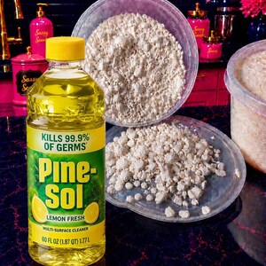 May include: A clear plastic bottle of yellow Pine-Sol Lemon Fresh multi-surface cleaner with a yellow cap, positioned next to a clear plastic container and lid filled with small, irregular, off-white solid pieces of a granular substance.