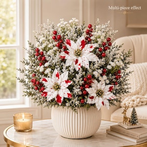 May include: A floral arrangement in a white ribbed ceramic bowl featuring three white poinsettias with red splatters, clusters of red berries, and white filler flowers mixed with green pine-like foliage. The text Multi-piece effect is visible.