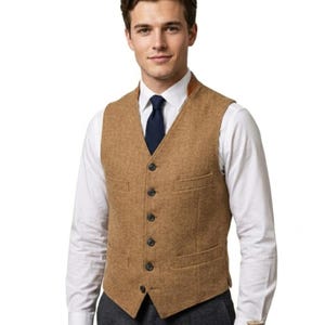 May include: A tan tweed vest with a V-neck, six dark buttons, and two front pockets. The vest is worn over a white dress shirt and a navy blue tie. The vest has a brown leather collar.