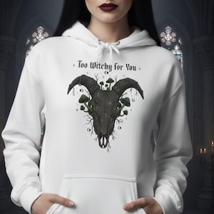 Puede incluir: Sudadera con capucha blanca con un diseño de calavera negra con cuernos y setas, con el texto "Too Witchy for You". La sudadera tiene una capucha con cordón y un bolsillo delantero.