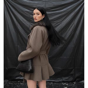 May include: A brown coat with a fur collar and a belted waist. The coat features a flared skirt and is worn with a black handbag and black boots. The background is a black backdrop.
