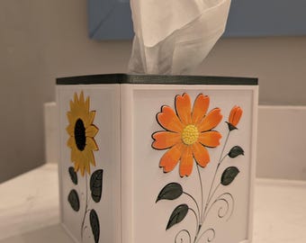 Funda para caja de pañuelos con diseño floral en relieve: girasol, cosmos, tulipán y clemátide.