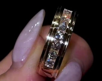 May include: A gold ring featuring five round diamonds set within a channel. The ring has a polished finish and a rectangular design. The diamonds sparkle against the gold band, creating a luxurious appearance.