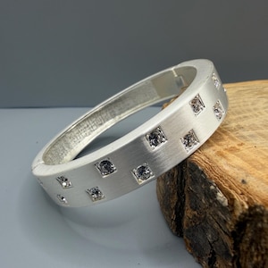 Peut inclure: Une tasse en céramique blanche avec une anse noire et le texte "But First, Coffee" en noir, dans une police manuscrite. La tasse est posée sur une surface blanche.