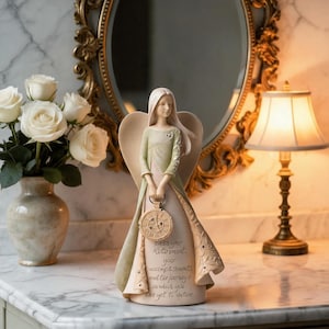 May include: A figurine of an angel with long hair wearing a pale green and cream gown, holding a round clock. The dress features the text: Bless your Retirement, your accomplishments and the journeys in which you have yet to venture.
