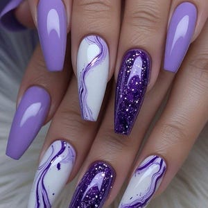 May include: A manicure featuring long, coffin-shaped artificial nails. The nails are decorated with solid lavender, white with purple marble patterns, and glittery purple designs. The overall look is sophisticated and fashionable.