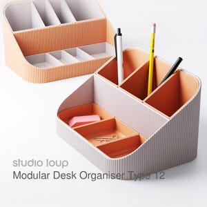 Könnte beinhalten: Zwei modulare Schreibtisch-Organizer in Pfirsich und Weiß. Die Organizer haben mehrere Fächer für Stifte, Bleistifte und andere Büroartikel. Der Text "studio loup Modular Desk Organiser Type 12" ist sichtbar.