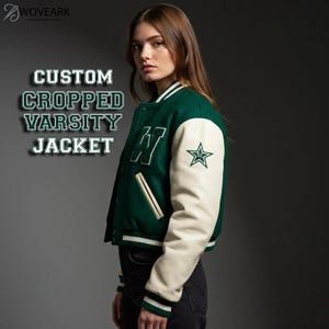 Pode incluir: Uma jaqueta varsity curta com corpo de lã verde-escura e mangas na cor creme. A jaqueta apresenta uma letra W branca grande no peito, um emblema de estrela na manga esquerda e punhos listrados. O texto diz CUSTOM CROPPED VARSITY JACKET.
