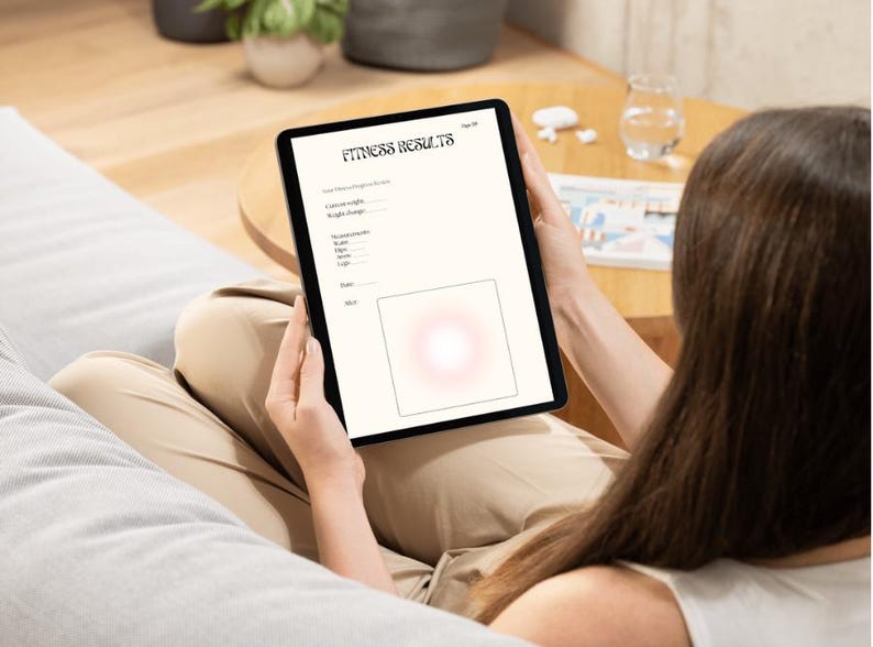 May include: A black tablet displaying a fitness results form with the title "Fitness Results". The form includes fields for weight, measurements, and other data. The tablet is held by a person.