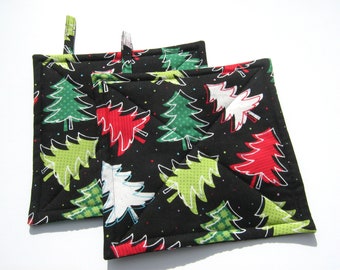 May include: Two black quilted pot holders with a Christmas tree pattern. The trees are green, red, and white with a black background and white polka dots.