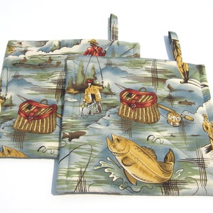 May include: Set of three green and brown fabric pot holders with a fishing theme. The pot holders feature images of fishermen, fishing baskets, and fish.